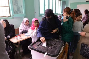 Woman casts her ballot in Egypt's 2014 constitutional referendum as child looks on © Bora S. Kamel | Flickr