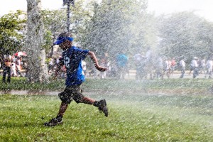 A boy playing in the water being sprayed from a DC Fire Department firetruck on a hot summer day. © The Q Speaks | Flickr